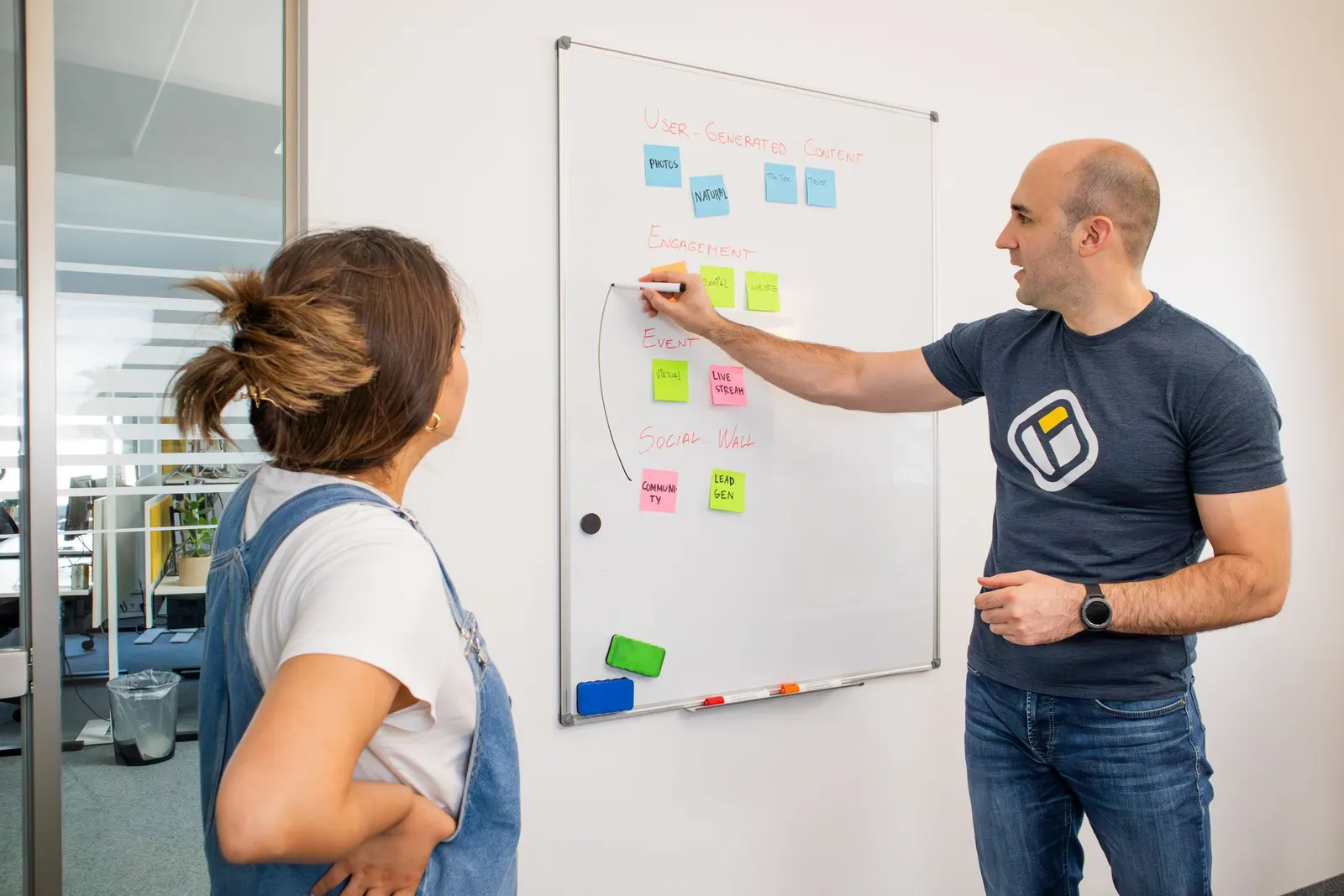 Two colleagues planning work on a whiteboard